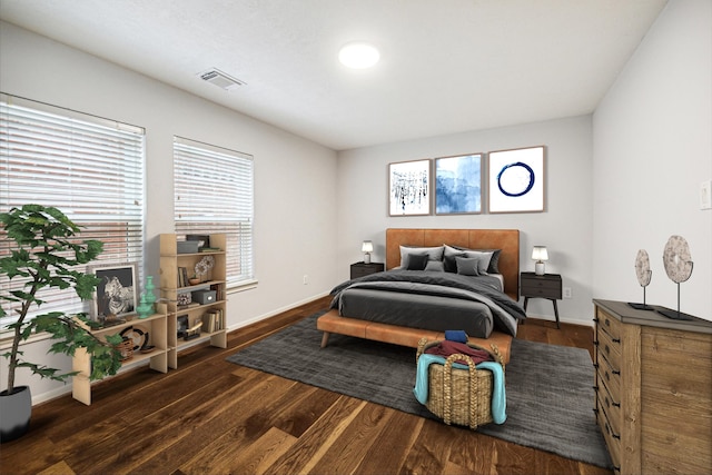 bedroom featuring baseboards, wood finished floors, visible vents, and multiple windows