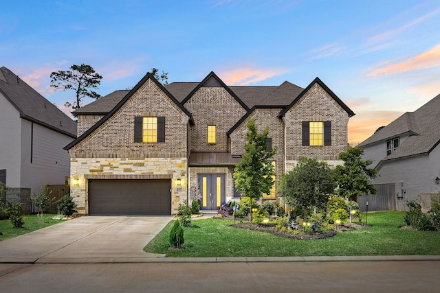view of front facade with an attached garage, a yard, driveway, and brick siding