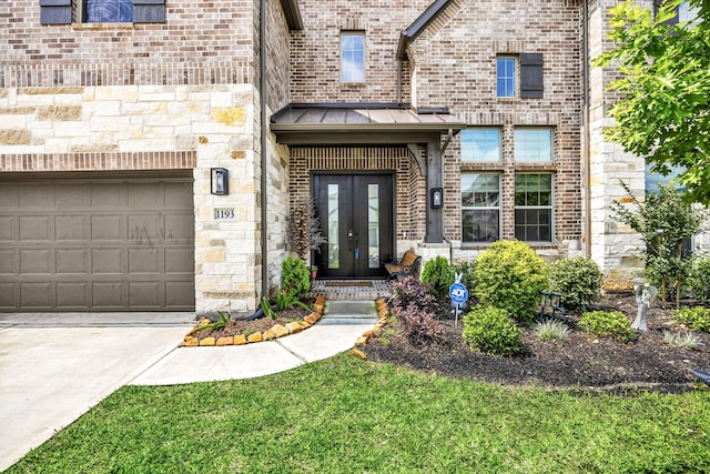 property entrance featuring brick siding, a garage, a standing seam roof, french doors, and driveway