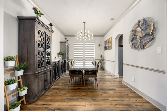 dining space featuring arched walkways, a chandelier, wood finished floors, visible vents, and ornamental molding