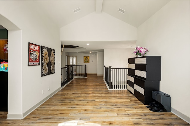 hall with visible vents, baseboards, beamed ceiling, an upstairs landing, and light wood-style flooring