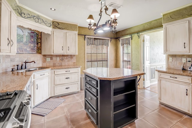 kitchen featuring stainless steel range with gas cooktop, visible vents, tasteful backsplash, and a sink