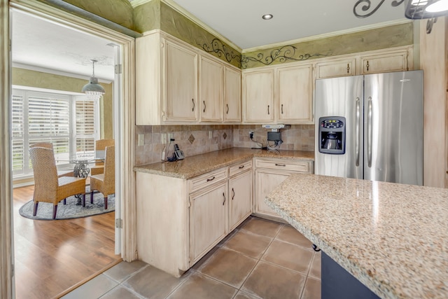 kitchen featuring tasteful backsplash, light stone counters, light tile patterned floors, stainless steel fridge with ice dispenser, and crown molding