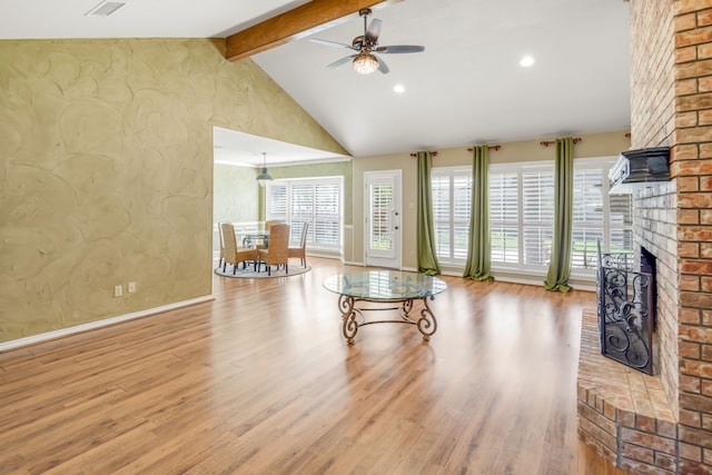 living room featuring a ceiling fan, beam ceiling, wood finished floors, and a fireplace