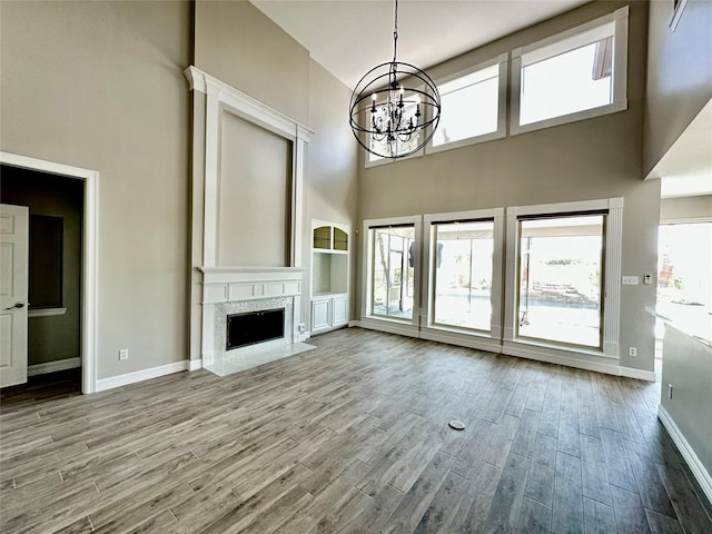 unfurnished living room featuring a wealth of natural light, wood finished floors, a notable chandelier, and a high ceiling