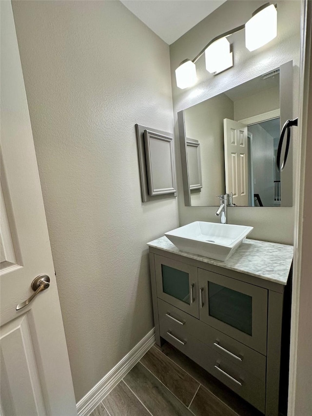 bathroom with vanity, wood finished floors, and baseboards