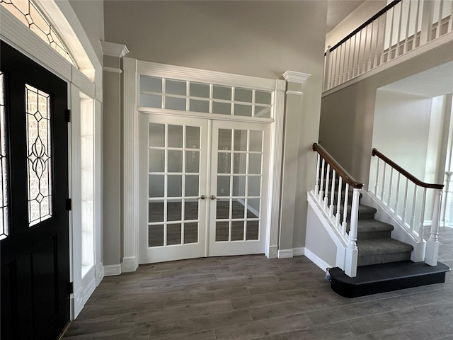 entryway featuring wood finished floors, stairway, baseboards, french doors, and a high ceiling