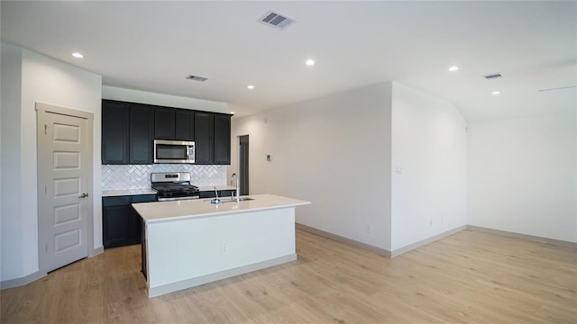 30106 Reagans Ranch Dr, Katy, TX 77494 - kitchen featuring stainless steel appliances, dark cabinetry, visible vents, backsplash, and light countertops