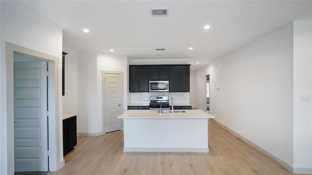 30106 Reagans Ranch Dr, Katy, TX 77494 - kitchen featuring dark cabinets, appliances with stainless steel finishes, a sink, visible vents, and light countertops
