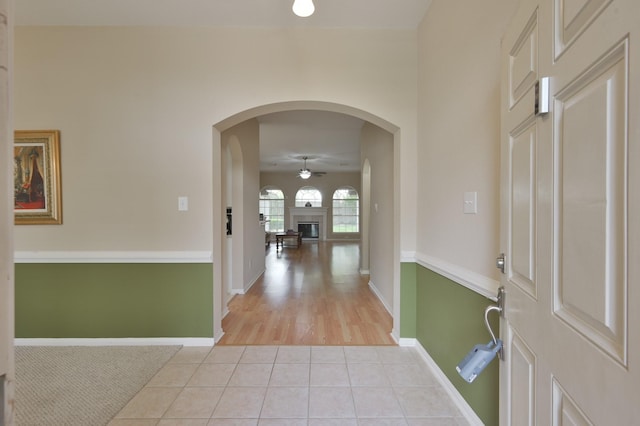 4719 Meadows Edge Ln, Houston, TX 77084 - entrance foyer featuring ceiling fan, light tile patterned floors, a fireplace with raised hearth, baseboards, and arched walkways