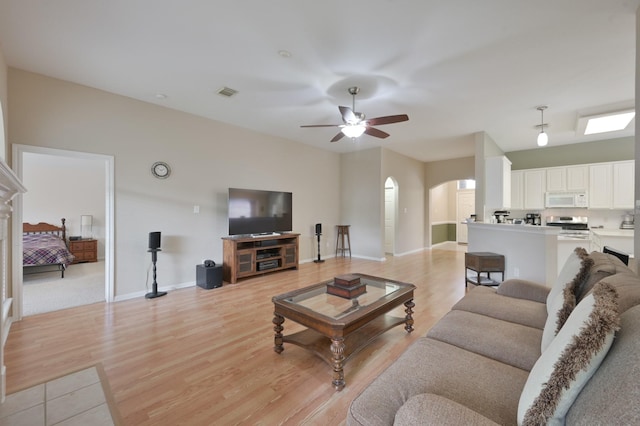 4719 Meadows Edge Ln, Houston, TX 77084 - living room featuring a ceiling fan, light wood-style flooring, arched walkways, and baseboards