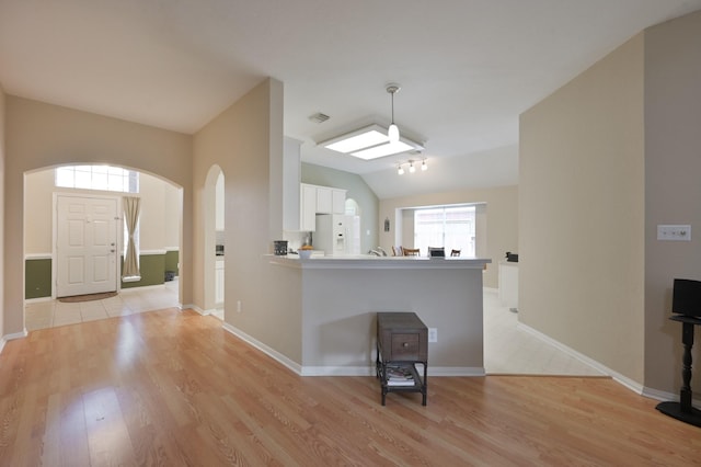 4719 Meadows Edge Ln, Houston, TX 77084 - unfurnished living room featuring light wood-style floors, lofted ceiling, arched walkways, and baseboards