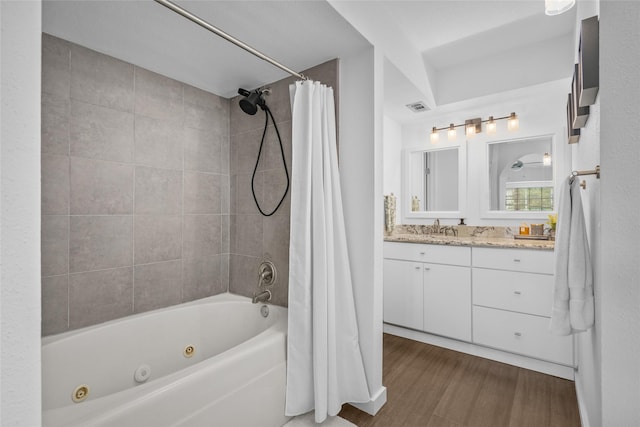 full bath featuring vanity, visible vents, a combined bath / shower with jetted tub, and wood finished floors
