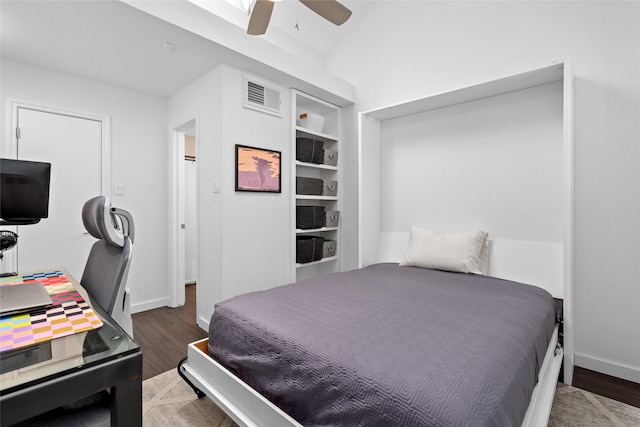 bedroom featuring baseboards, a ceiling fan, visible vents, and wood finished floors