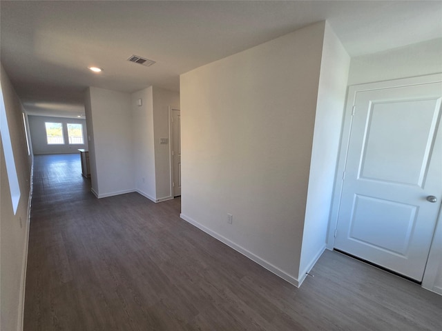 hall featuring dark wood-type flooring, visible vents, recessed lighting, and baseboards