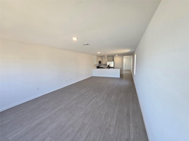 unfurnished living room with dark wood finished floors, baseboards, and recessed lighting
