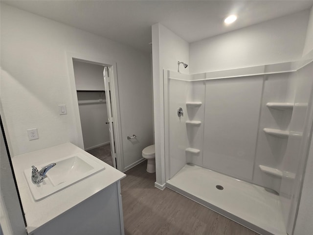 full bathroom featuring a shower stall, vanity, toilet, baseboards, and wood finished floors