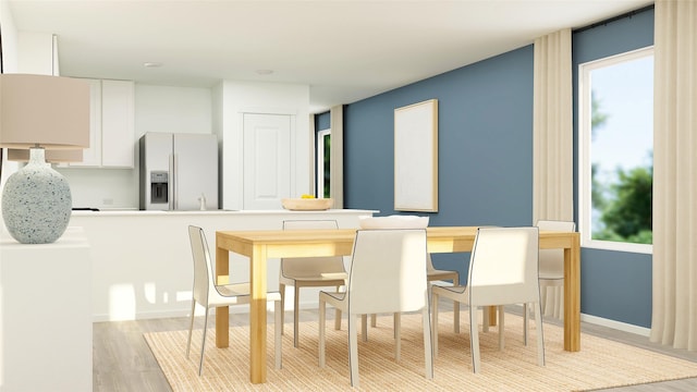 dining space featuring light wood-style floors and baseboards