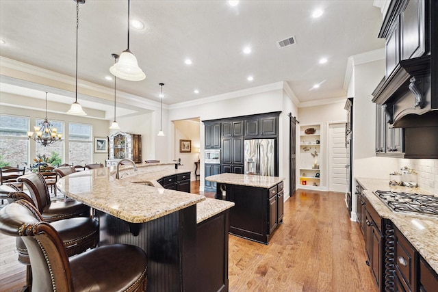 19907 Cullen Ridge Dr, Porter, TX 77365 - kitchen with visible vents, stainless steel appliances, a large island, a sink, and light wood-type flooring