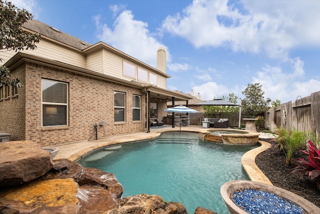 view of swimming pool featuring a pool with connected hot tub, a patio, and a fenced backyard