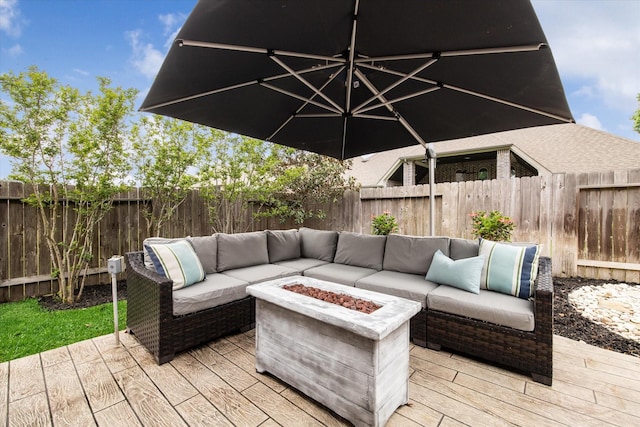 wooden terrace featuring an outdoor living space with a fire pit and a fenced backyard