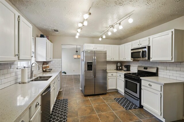 kitchen with a sink, appliances with stainless steel finishes, tasteful backsplash, and white cabinetry