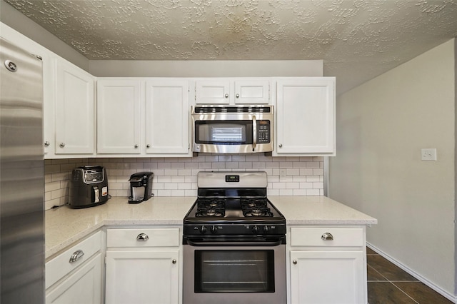 kitchen featuring white cabinets, stainless steel appliances, baseboards, and tasteful backsplash