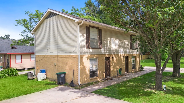 215 N Howard St, Tomball, TX 77375 - view of property exterior with a yard, brick siding, and central AC unit