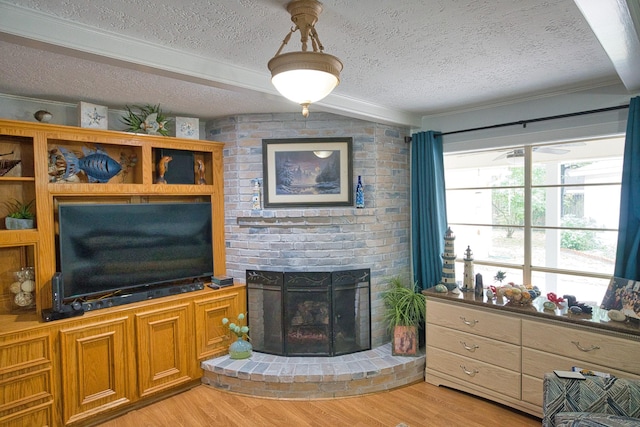living area featuring a textured ceiling, light wood finished floors, and a brick fireplace