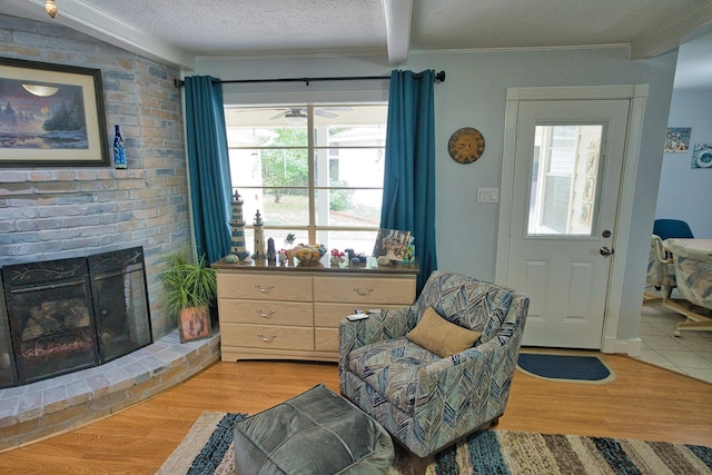 interior space with light wood-type flooring, a ceiling fan, ornamental molding, and a brick fireplace