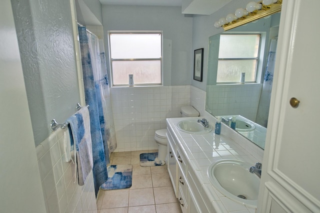 full bathroom featuring tile patterned floors, a sink, a wainscoted wall, and tile walls