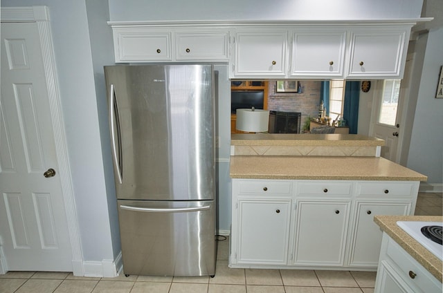 kitchen with light tile patterned floors, white cabinetry, freestanding refrigerator, and light countertops