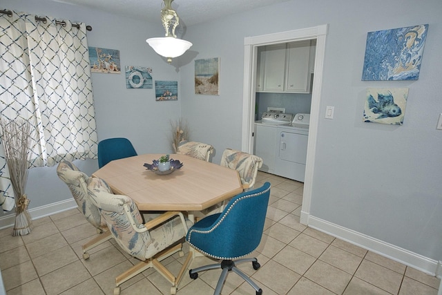 dining area with baseboards, light tile patterned floors, and washing machine and clothes dryer