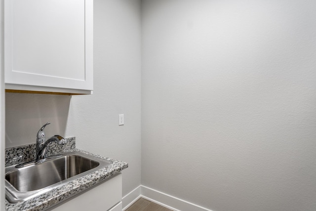 17311 Sunflower Petals Trl, Conroe, TX 77302 - details featuring a sink, white cabinets, and baseboards