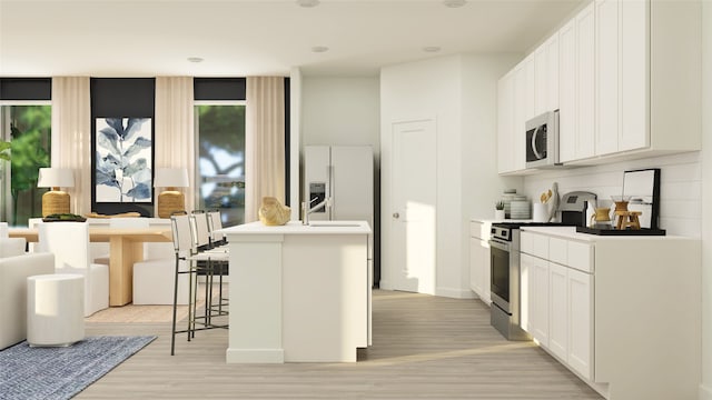 kitchen with light wood finished floors, decorative backsplash, stainless steel electric range oven, a center island with sink, and refrigerator with ice dispenser