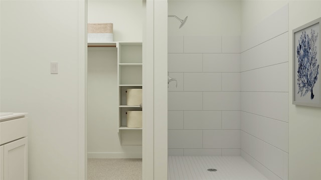 bathroom with a spacious closet, vanity, and a stall shower