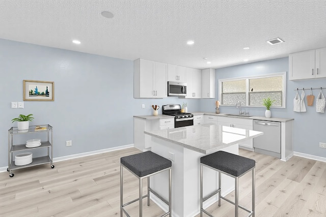 kitchen featuring a kitchen breakfast bar, a sink, stainless steel appliances, and a textured ceiling