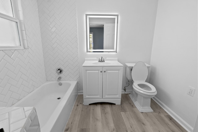 full bathroom featuring a bathing tub, baseboards, toilet, wood finished floors, and vanity