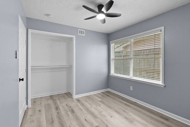 unfurnished bedroom with a textured ceiling, visible vents, light wood finished floors, and baseboards