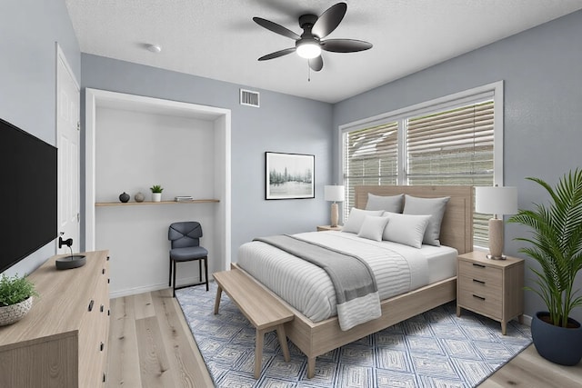 bedroom with a ceiling fan, visible vents, a textured ceiling, and light wood-type flooring