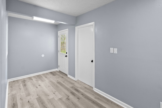 spare room with baseboards, wood finished floors, and a textured ceiling