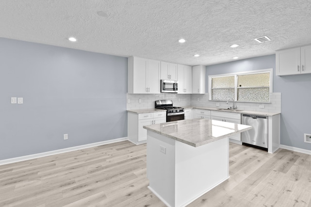kitchen featuring a sink, light wood-style flooring, stainless steel appliances, and decorative backsplash