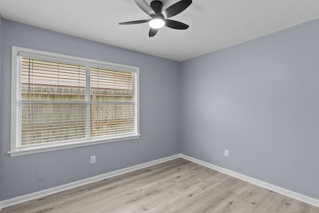 unfurnished room with baseboards, ceiling fan, a textured ceiling, and light wood-style flooring