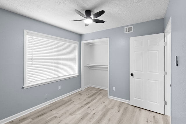 unfurnished bedroom featuring a closet, visible vents, wood finished floors, and a textured ceiling