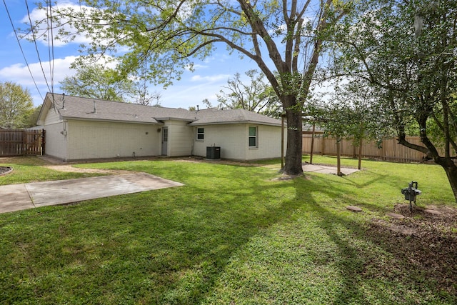 rear view of house with a fenced backyard, a yard, brick siding, a patio, and central AC unit