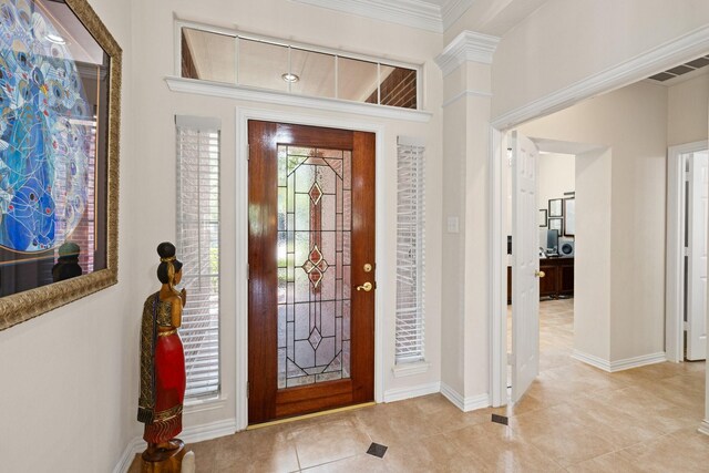 foyer with crown molding, light tile patterned flooring, and baseboards