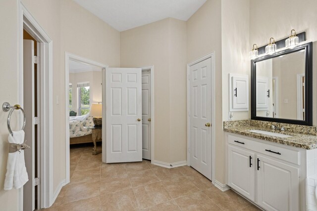 bathroom featuring baseboards, ensuite bathroom, tile patterned flooring, and vanity