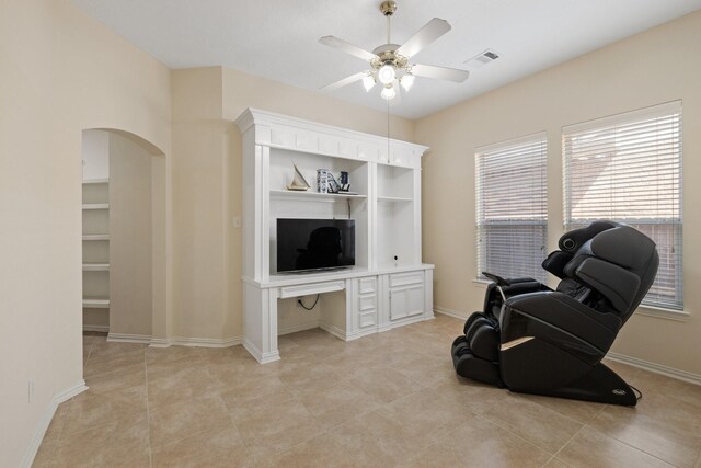 living area with a ceiling fan, visible vents, arched walkways, light tile patterned floors, and baseboards