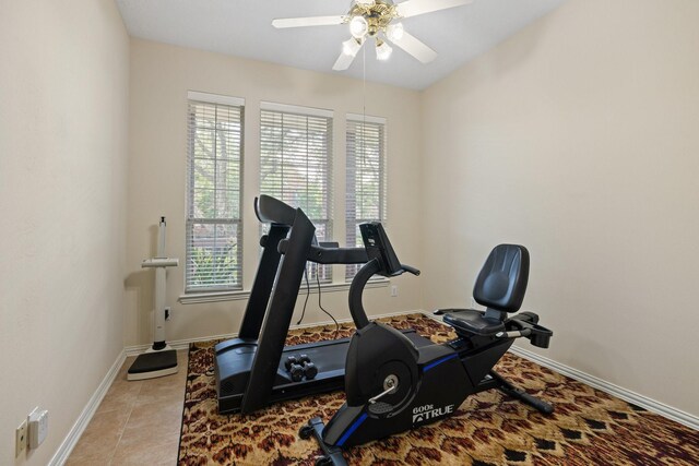 exercise room with baseboards, a ceiling fan, and tile patterned flooring