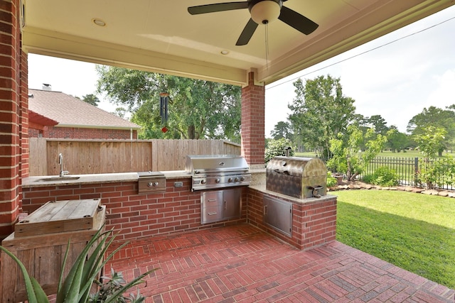 view of patio / terrace featuring grilling area, ceiling fan, a sink, a fenced backyard, and an outdoor kitchen